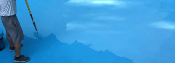 Profissional realizando o serviço de pintura de piscinas de fibra